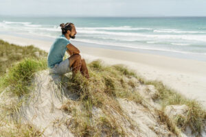 Dispirited man sitting on beach gazing at sea