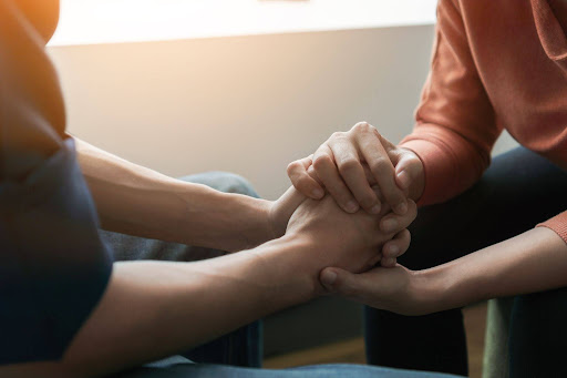 Person holding another person’s hands in supportive moment, representing mental health safety planning, connection, and suicide prevention support