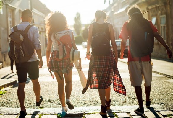 Rear view of four touristic friends walking down the street.