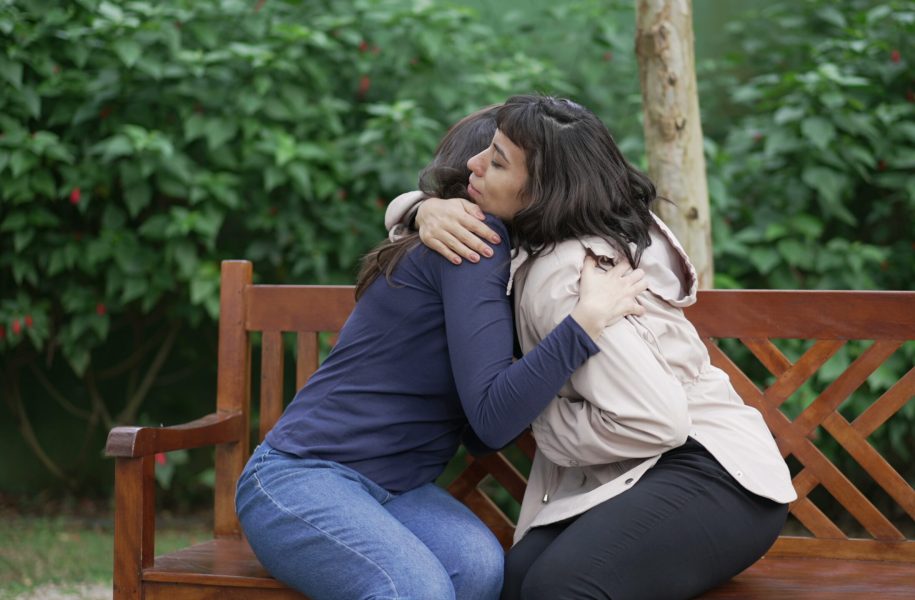 Sympathetic female friend in SUPPORT with suffering woman. Person in sorrow embracing supportive companion